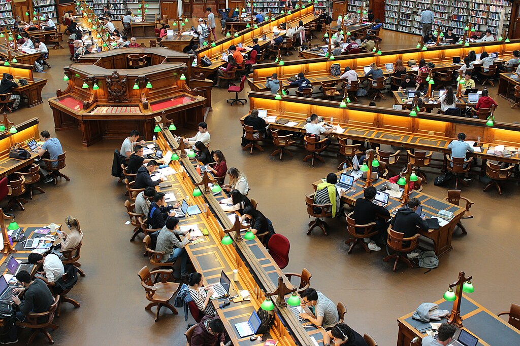 photograph of a library reading room full of patrons shot from above